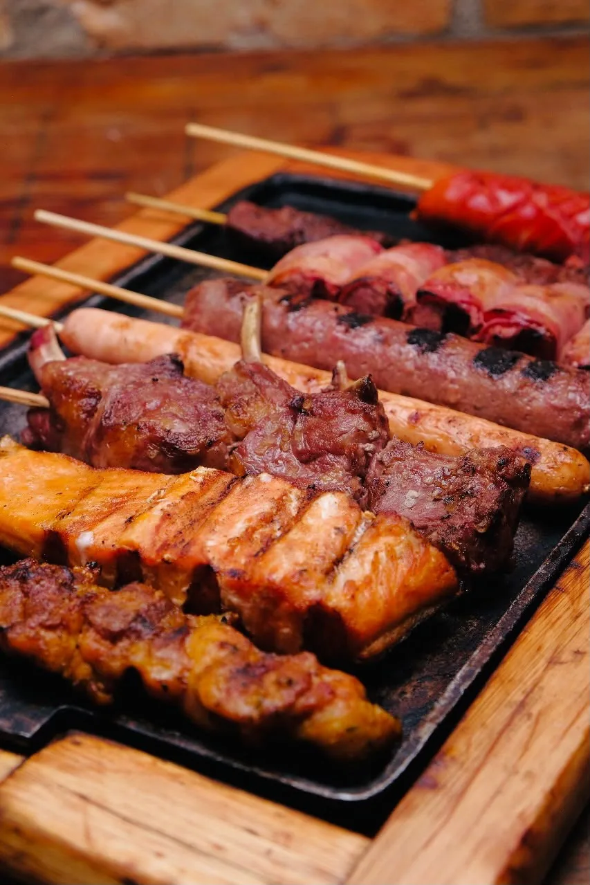 Espetos mistos — carnes, linguiça e queijo coalho — na grelha.