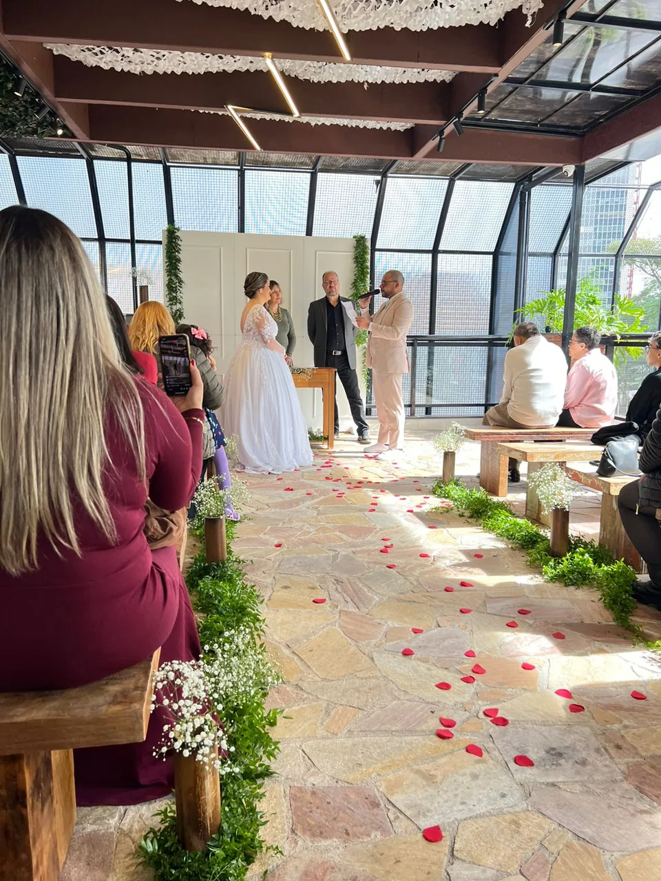 Casal se casando no rooftop do Perobah Pinheiros, com convidados sentados e a cidade ao fundo.